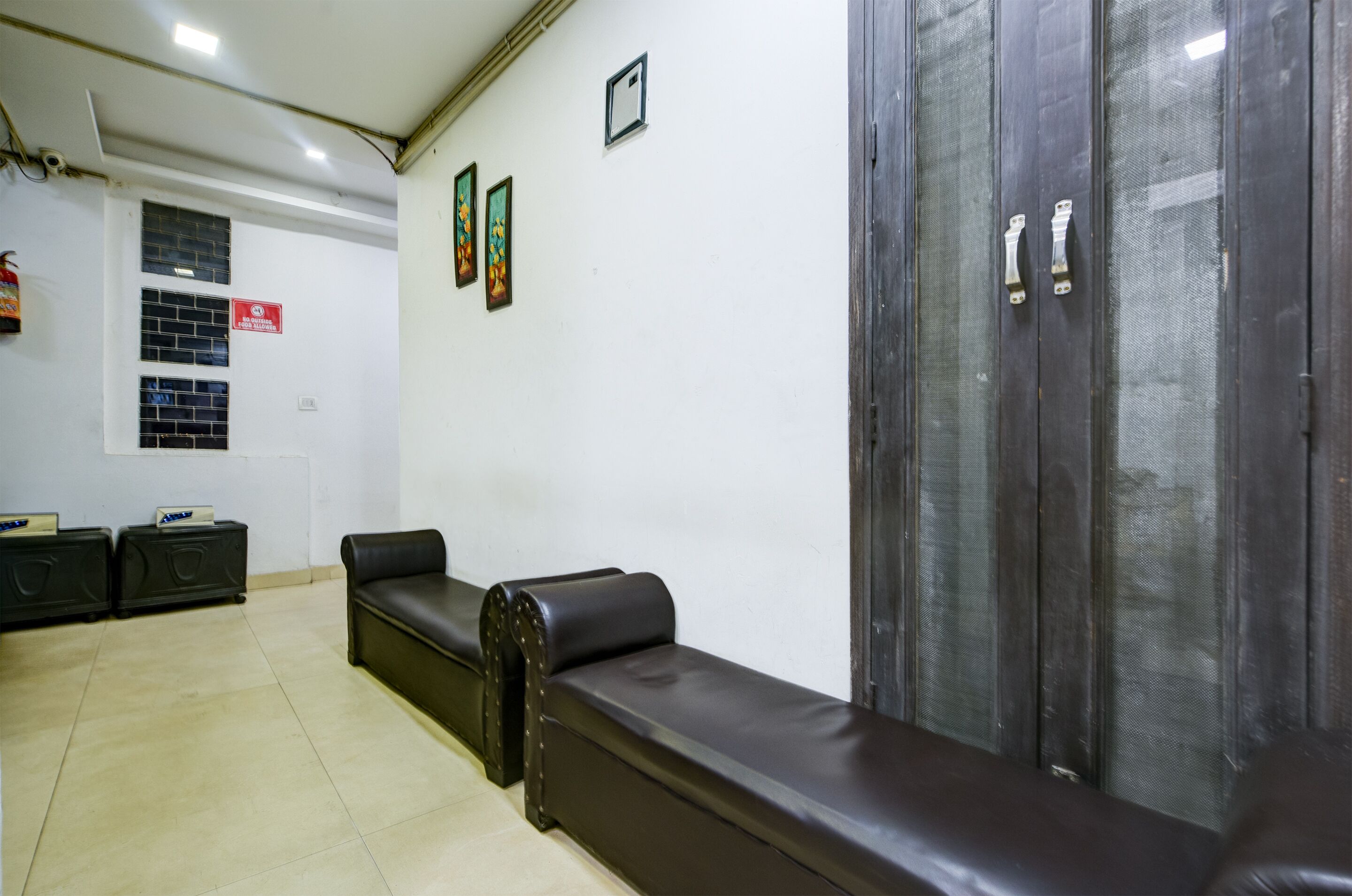 A waiting area with a leather bench, a glass partition, and a wall-mounted fire extinguisher.