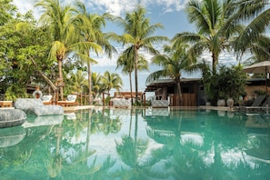 Una piscina al aire libre, sombrillas, sillones reclinables de piscina