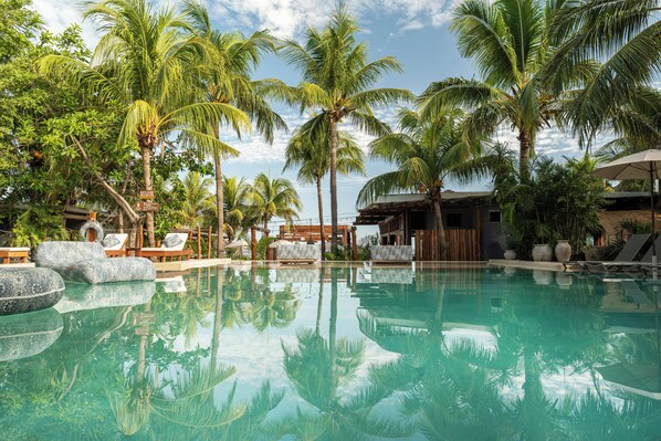 Una piscina al aire libre, sombrillas, sillones reclinables de piscina