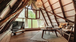 A cozy, rustic room with a wooden floor, a flat-screen TV, a sofa, and a table. - Hotel Villas Caracol (Isla Holbox)