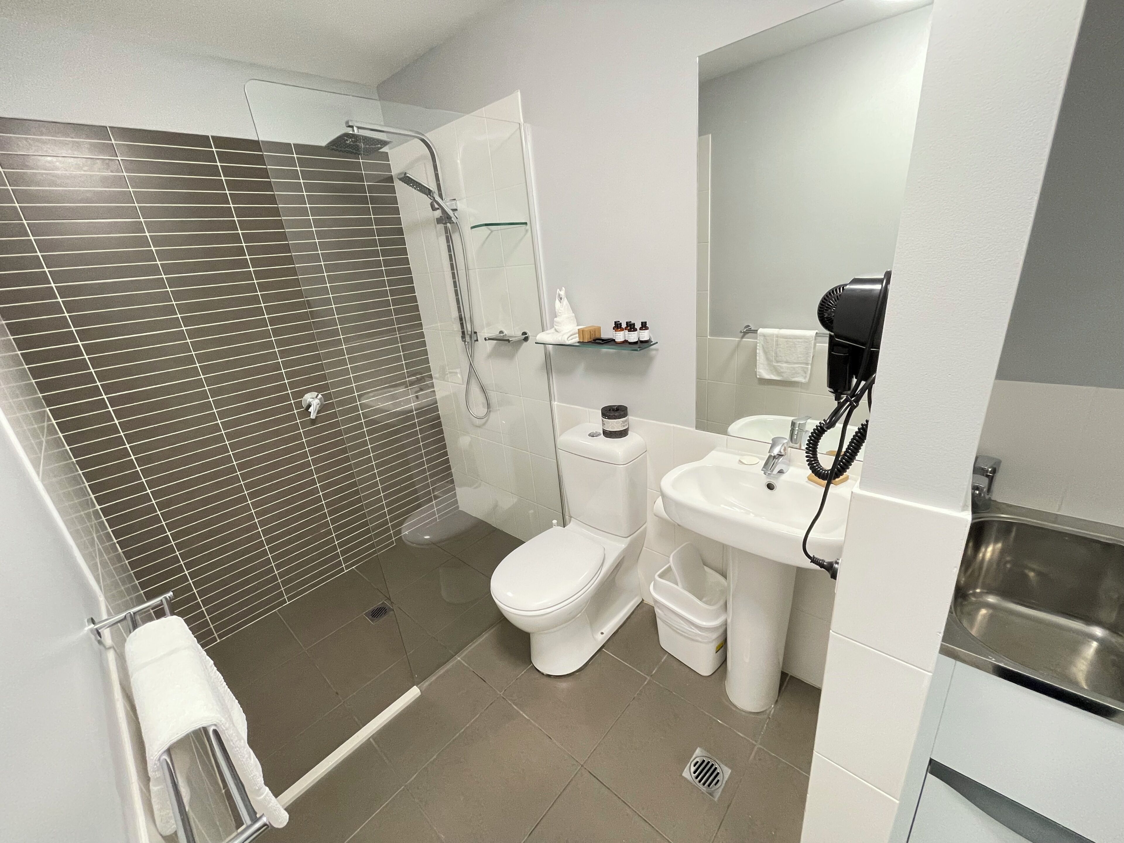 Une salle de bain moderne équipée d’une douche, de toilettes, d’un lavabo et d’un miroir.