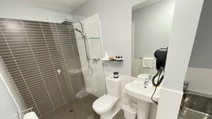 Een moderne badkamer met douche, toilet, wastafel en een spiegel.