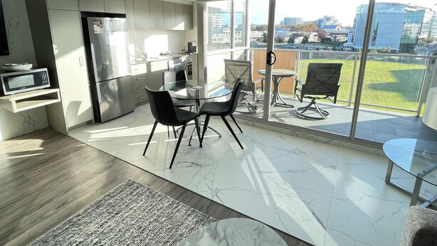 A modern kitchen with a dining area and a balcony with a city view. - Premium One Bedroom Apartment (Newcastle)