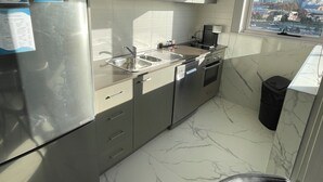 Une cuisine moderne dotée d’appareils électroménagers en acier inoxydable, d’une fenêtre offrant une vue sur la ville et d’un revêtement de sol en marbre.