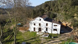 A white building with a tiled roof, surrounded by a grassy area and trees.