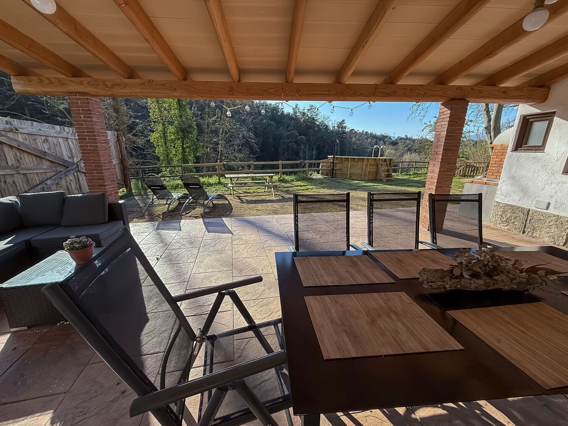 Eine Außenpatio mit Holz-Pergola, Sitzgelegenheit und Blick auf die umliegende Landschaft.
