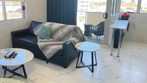 A modern living room with a sofa, a coffee table, a side table, and a balcony with a chair.
