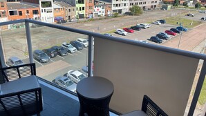 A balcony with a view of a parking lot and surrounding buildings.