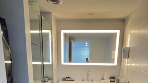A modern bathroom with a glass shower enclosure, a white sink with a mirror above, and a toilet. - Standard Two Bedroom (Newcastle)
