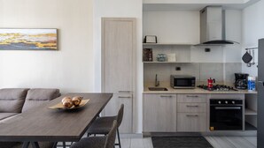 Een moderne keuken met een eethoek, met een houten tafel, stoelen, een magnetron, een fornuis en een koffiezetapparaat.