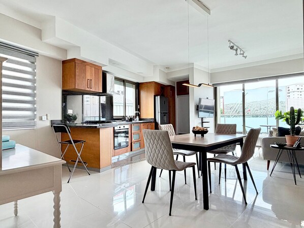 A modern kitchen with a dining area, large windows, and a view of the city.