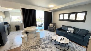Un salon moderne avec un canapé bleu foncé, une table basse ronde et un coin repas comprenant une petite table et des chaises.