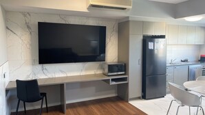 Eine moderne Küche mit Marmor-Spritzschutz, einem Flachbildfernseher, einer Mikrowelle, einem Kühlschrank und einem Essbereich mit Stühlen.