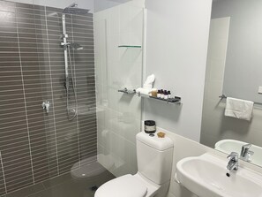 Enjoy a refreshing shower in the sleek bathroom with a handheld showerhead and glass-enclosed toilet.