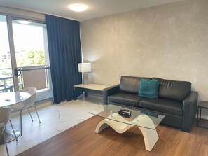 Relax in a stylish living area with a comfortable sofa, glass coffee table, and a large window offering a view of the outdoors.