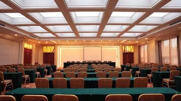 A conference room with a high ceiling, multiple tables, and chairs arranged for meetings.