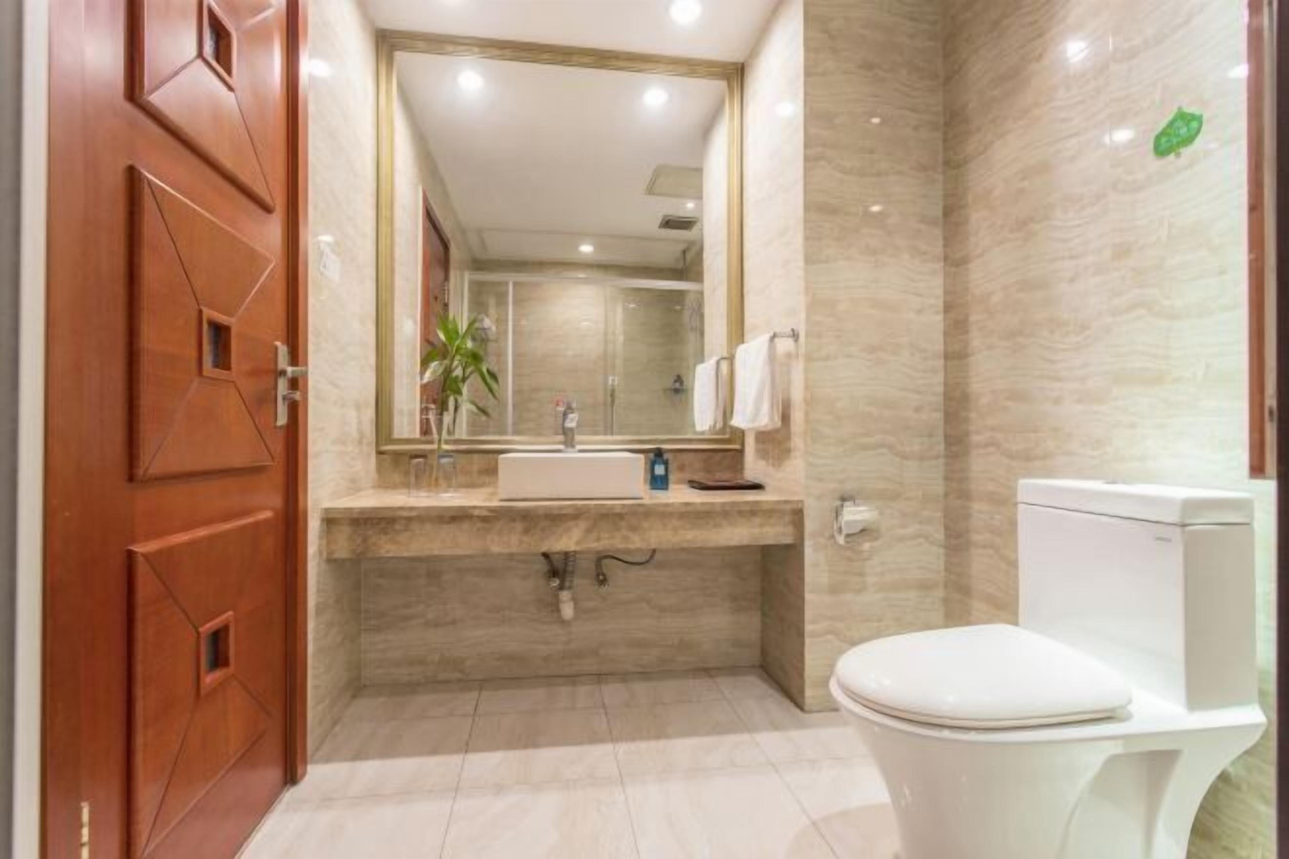 Un baño moderno con lavamanos, espejo e inodoro.