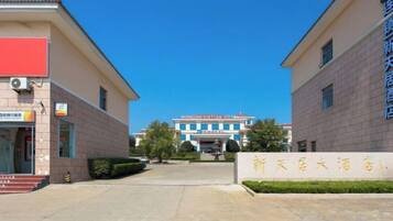 A hotel entrance with a clear sky, a signboard, and a building in the background.