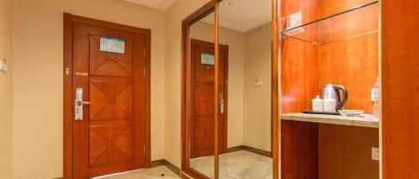 Une chambre d’hôtel avec une porte en bois, un grand miroir et une étagère contenant des articles de toilette.