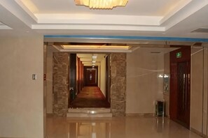 A hotel corridor with a polished floor, a red carpet, and a modern light fixture. - Xintian Hotel (Fei County)