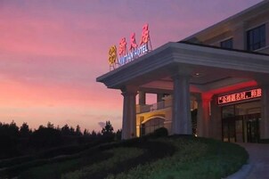 A hotel entrance with a sign indicating 'Xiantian Hotel' and a covered walkway leading to the entrance.