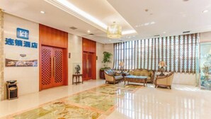 Un vestíbulo de hotel con piso a cuadros, una recepción y un área de descanso con sofás y lámparas.