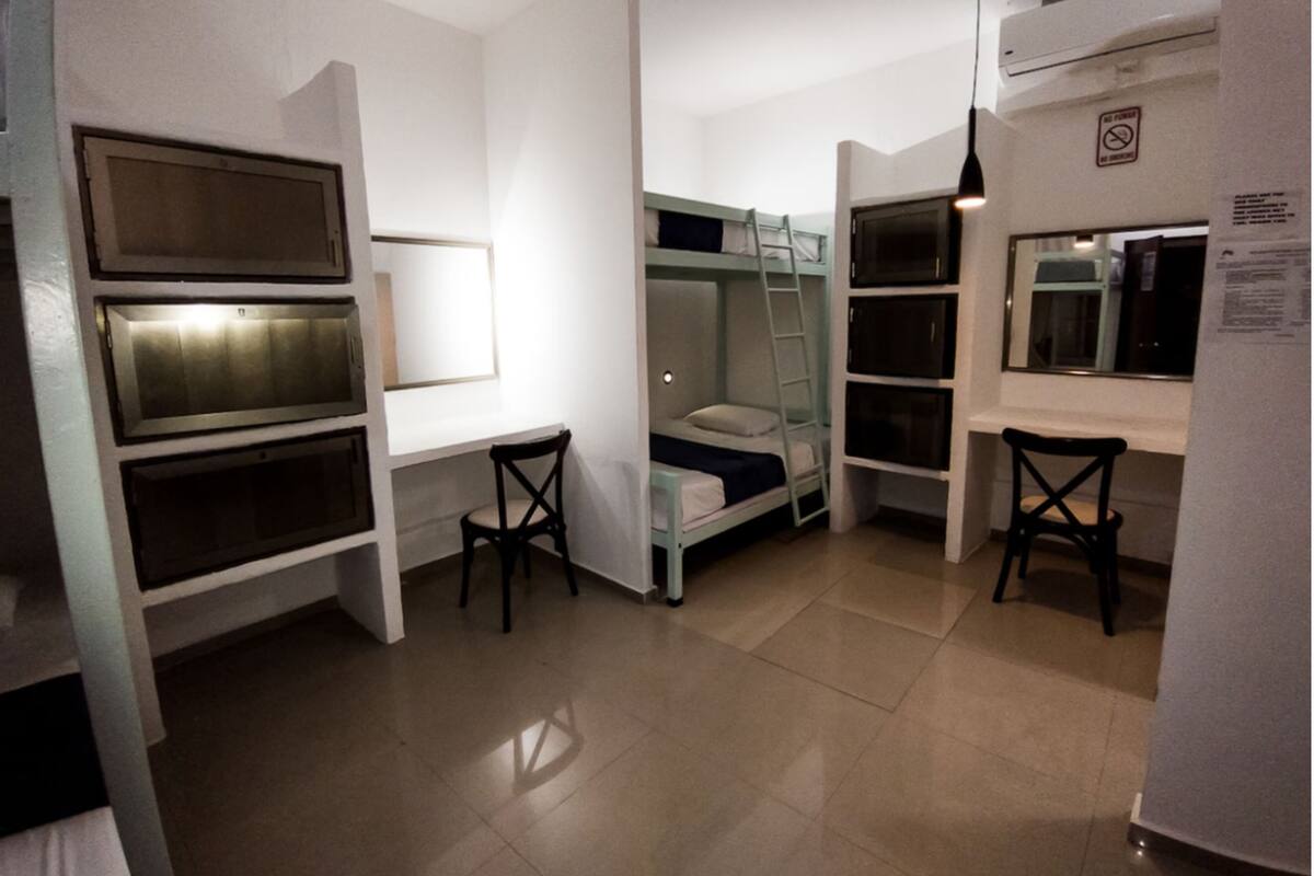 A compact room with bunk beds, a desk, and built-in shelves.