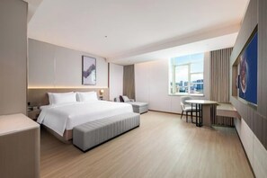 A hotel room with a large bed, a desk, a chair, a window with a city view, and a mounted artwork. - Lavande Hotel Shenzhen Longgang Dayun Center Jixiang Metro Station (Shenzhen)