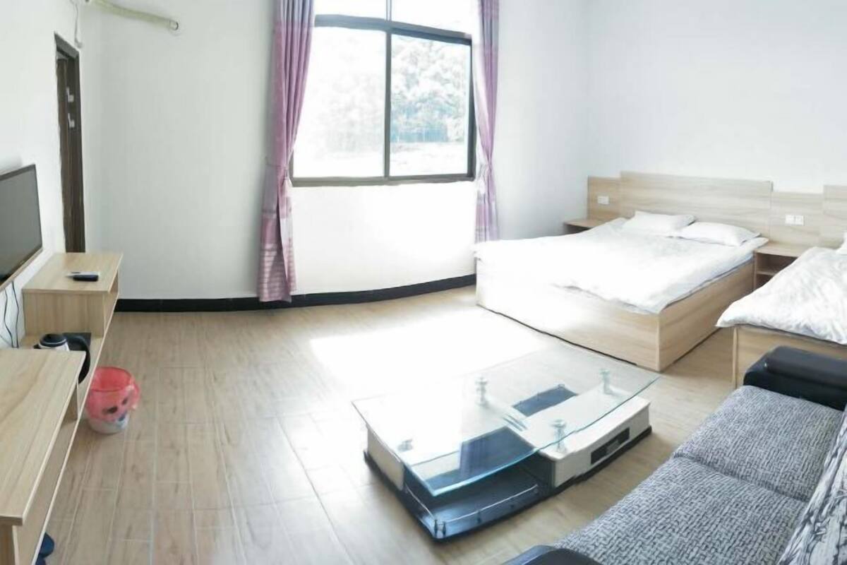 A hotel room with a bed, a sofa, a TV, a desk, and a window with curtains.