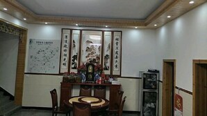 A conference room with a round table, chairs, a cabinet with items, and a wall with calligraphy. - Wuyuan Jiangling Garden Hostel (Wuyuan)