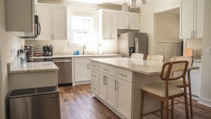 A modern kitchen with white cabinetry, a central island, and a small trash bin.