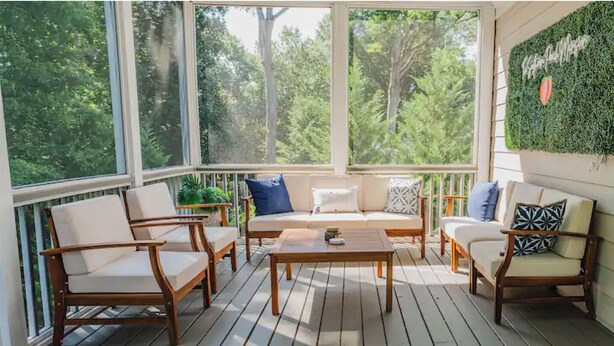 A sunlit wooden deck with a sofa, two armchairs, and a coffee table.