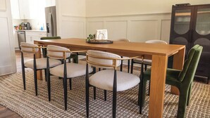 A dining area with a wooden table and six chairs, a kitchen in the background, and a decorative screen.