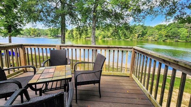 A wooden deck with a table and chairs overlooking a lake. - Better to WAKE at the LAKE (Hot Springs)