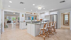 A spacious kitchen with a large island, white cabinetry, and stainless steel appliances. - Kon-Tiki Falls: Jupiter`s Exclusive Private Resort! (Jupiter)