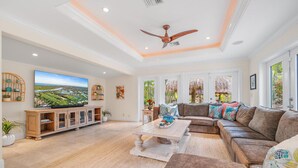 A spacious living room with a large sectional sofa, a flat-screen TV, and a ceiling fan. - Kon-Tiki Falls: Jupiter`s Exclusive Private Resort! (Jupiter)