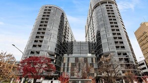 A modern building with a curved facade, multiple balconies, and a central glass section. - 2bd 2bth - Chic Apt in Woden CBD (Phillip)