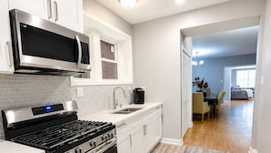 Una cocina moderna con gabinetes blancos, estufa de acero inoxidable y microondas.