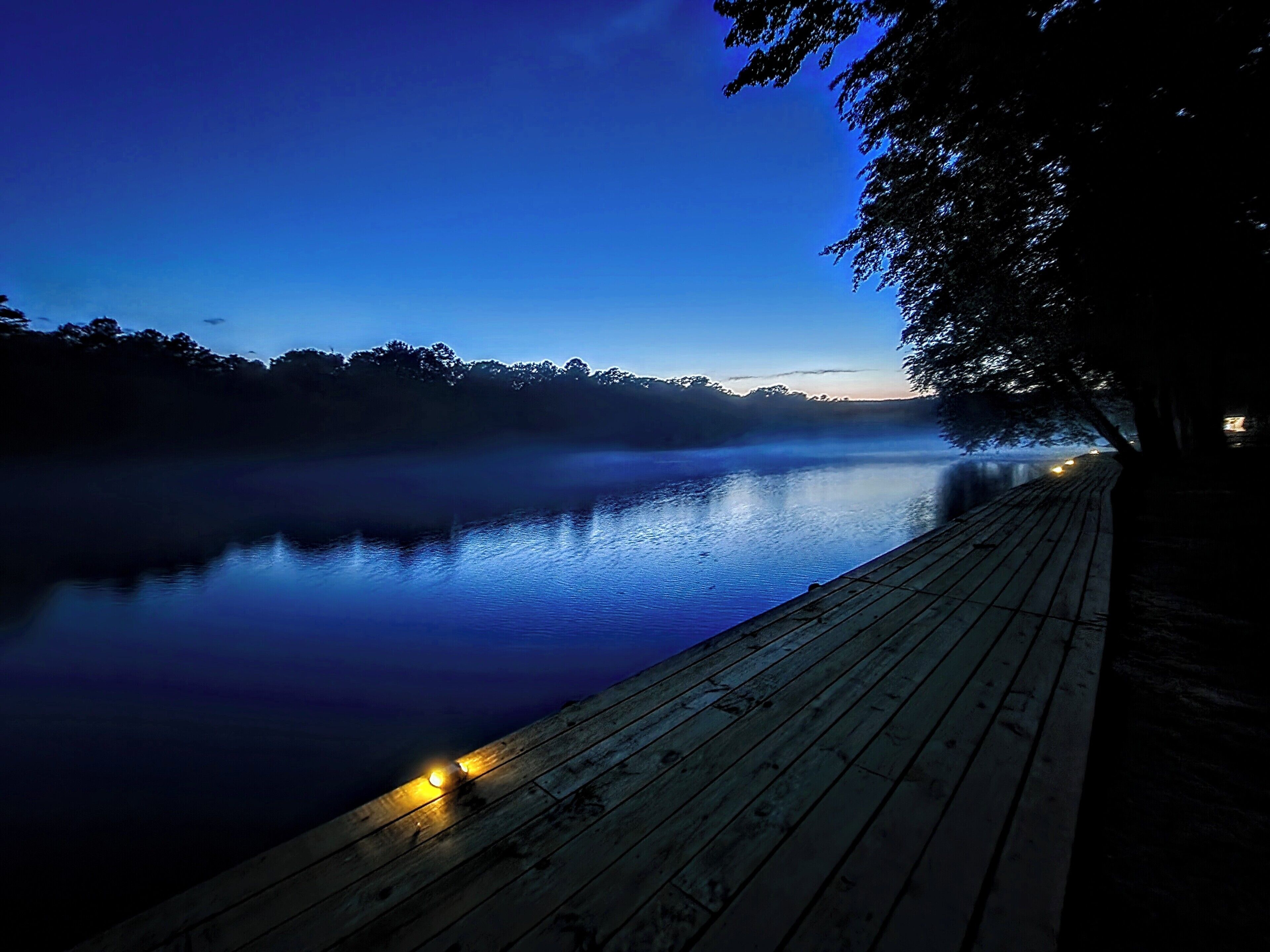 A wooden dock extending into a calm body of water at dusk.