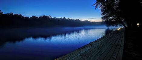 A wooden dock extending into a calm body of water at dusk.