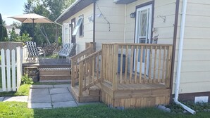 Eine Holzterrasse mit Geländer, einem weißen Zaun und einer überdachten Veranda mit Sitzgelegenheiten.