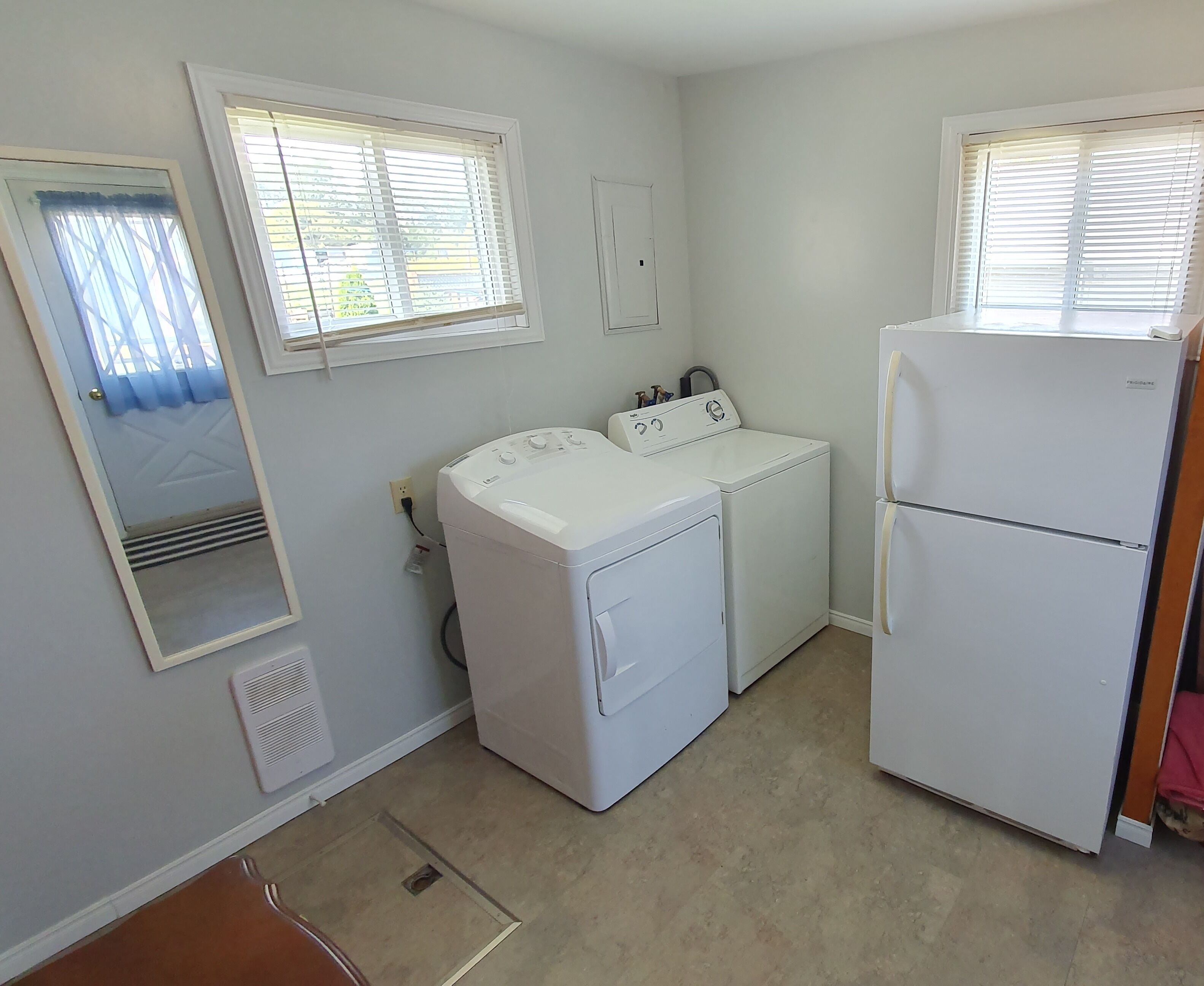 A laundry room with a washer, dryer, and refrigerator.