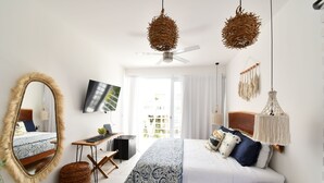 A modern bedroom with a large mirror, a bed with patterned bedding, a desk, and a ceiling fan. - Muuk Tulum by The Spot Rentals (Tulum)
