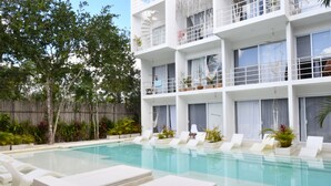 A modern hotel with a pool area, including lounge chairs and potted plants. - Muuk Tulum by The Spot Rentals (Tulum)