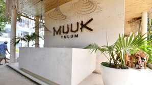 A reception area with a sign reading "MUUK TULUM" and a large potted plant. - Muuk Tulum by The Spot Rentals (Tulum)
