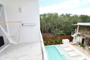 Un área de piscina moderna al aire libre con una hamaca, una piscina pequeña y una terraza de madera.