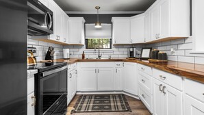 Una cocina moderna con armarios blancos, un horno negro y una encimera de madera.