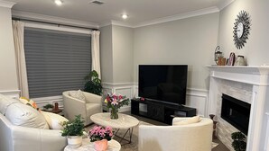 A living room with a sofa, armchairs, a coffee table, a TV, and a fireplace.