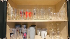 Une étagère de cuisine contenant divers objets en verre, notamment des verres et des verres à vin.