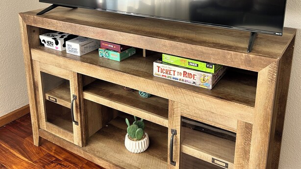 Ein Holz-Entertainment-Center mit Fernseher, Büchern und einer kleinen Kaktee.